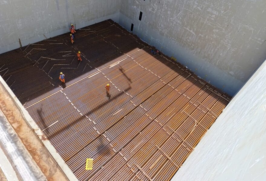 Trilhos dentro de porão de navio de projetos com trabalhadores preparando para a logística
